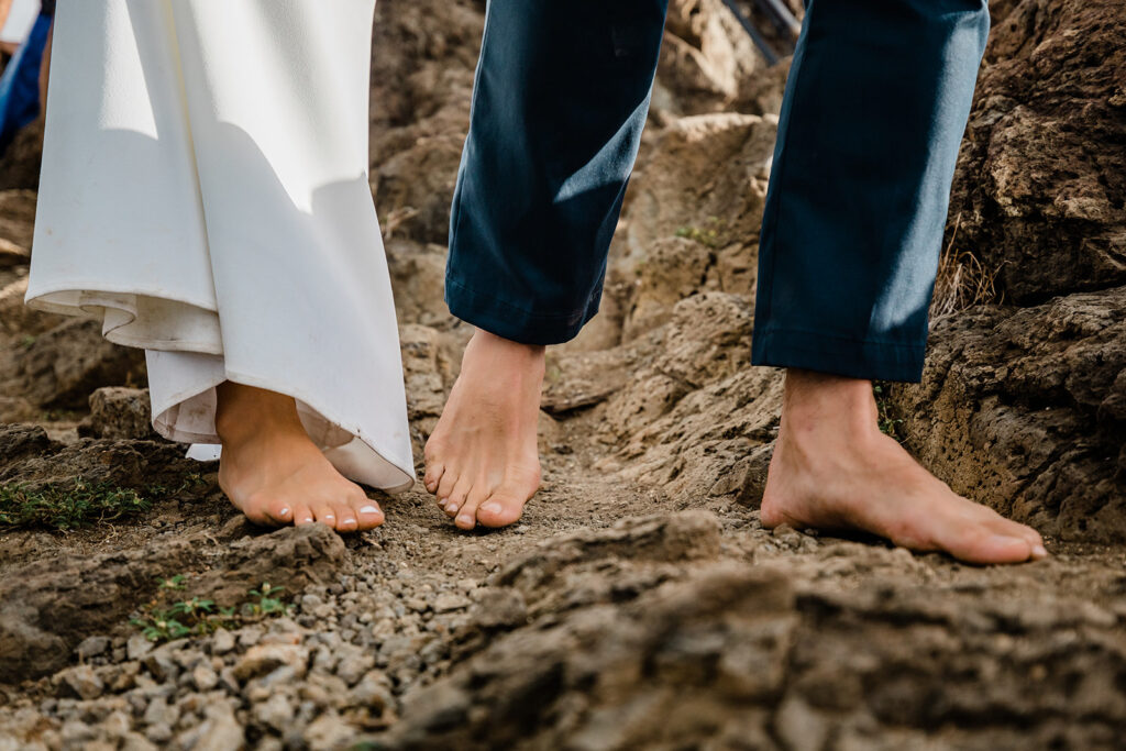 A couple walks barefoot towards their wedding ceremony on the beach in Hawaii