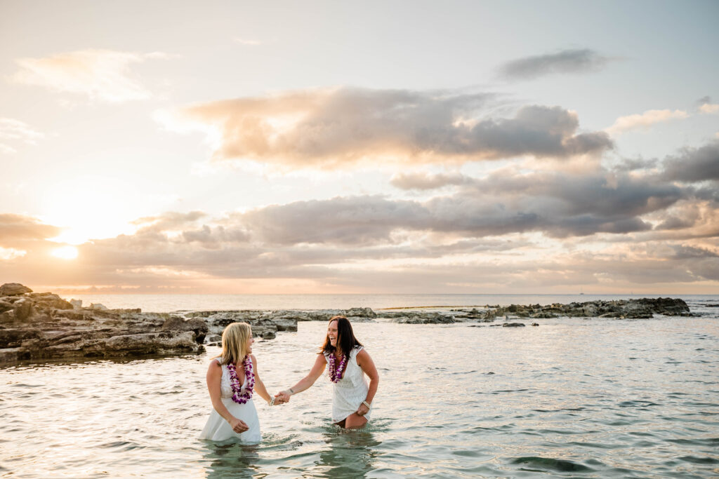 Two women splash in the water after their wedding ceremony in Hawaii