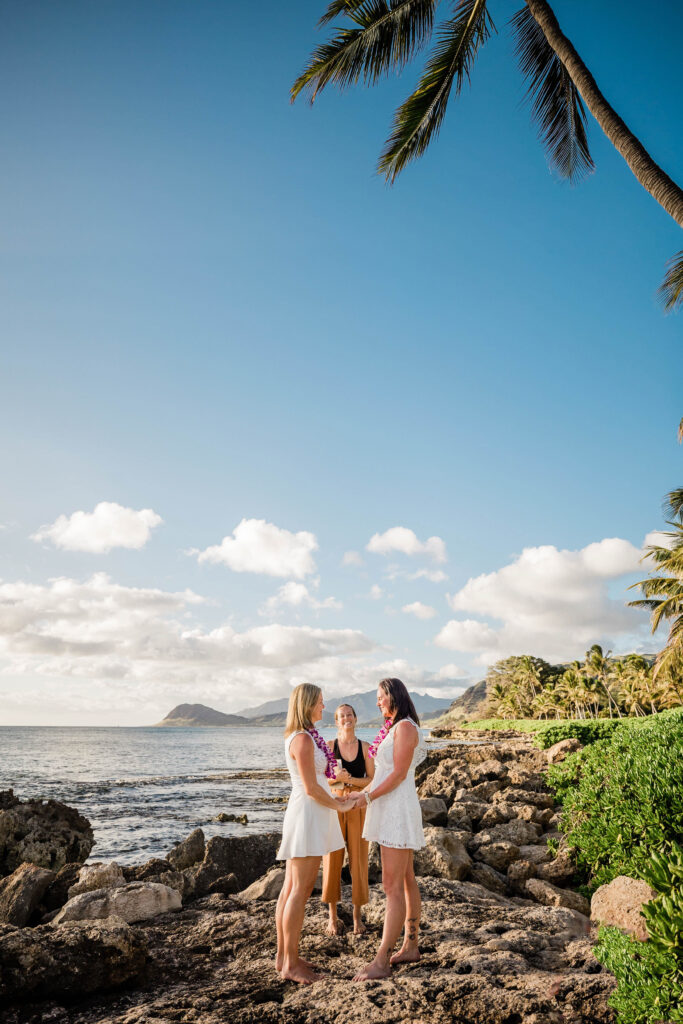 Two women get married on the cliffs on a beach in Hawaii.