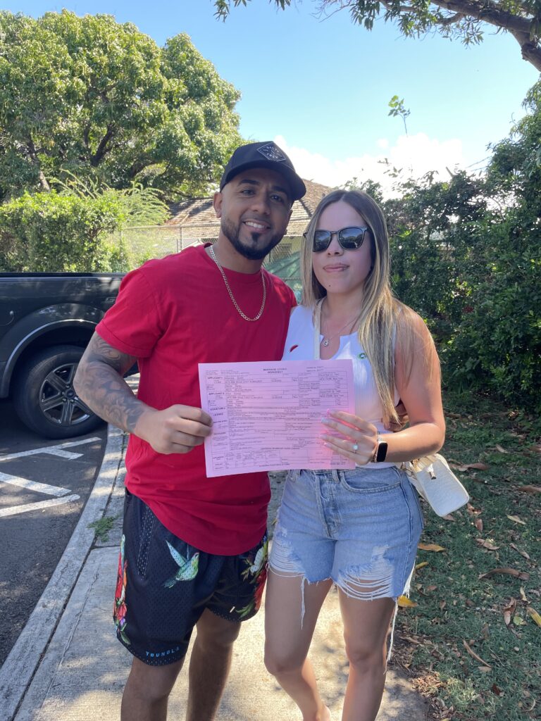 Couple holds up a picture of their marriage license in Oahu, Hawaii. 