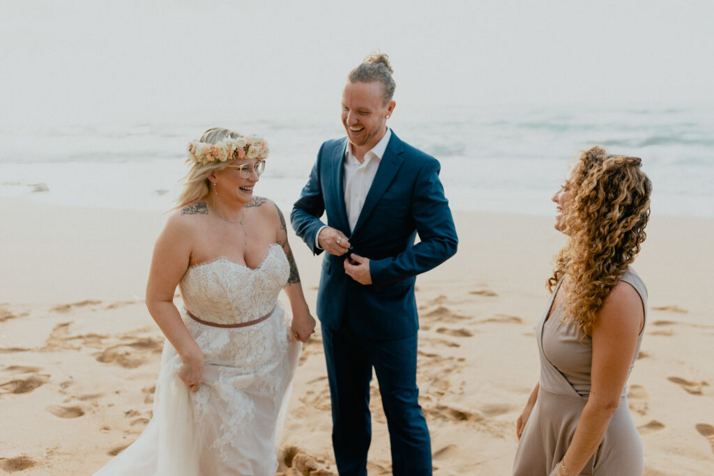 Couple stands on the beach on the North Shore of Oahu with their wedding officiant after getting married. 